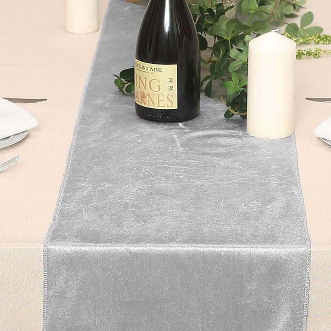 Gray velvet table runner with wine bottle and candles on a dining table.
