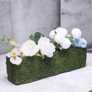 Artificial floral arrangement in a moss-covered planter.