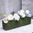 Artificial floral arrangement in a moss-covered planter.