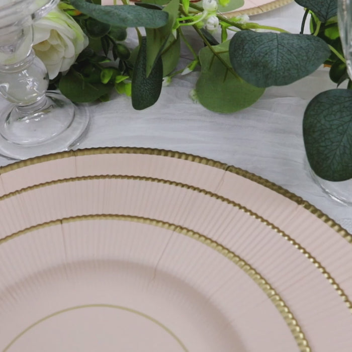 Blush charger plates with gold rim on a table setting.