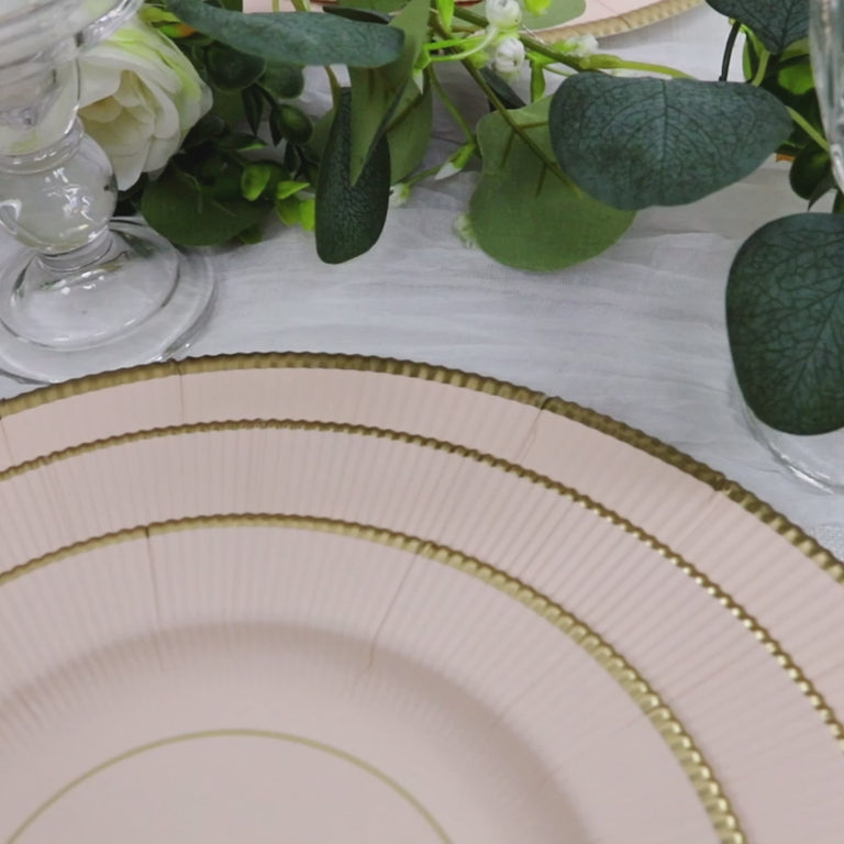 Blush charger plates with gold rim on a table setting.