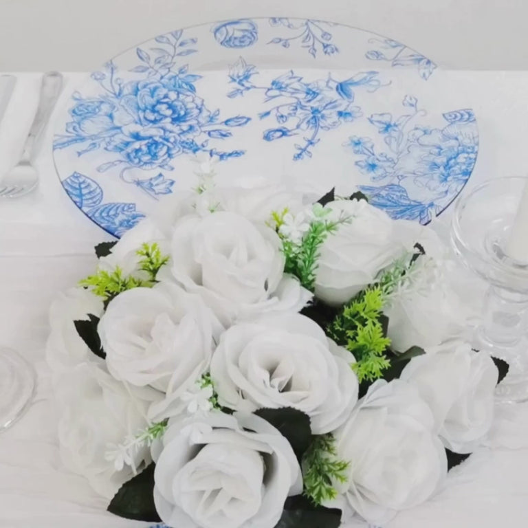 Clear light blue floral charger plate with white roses on a table setting.