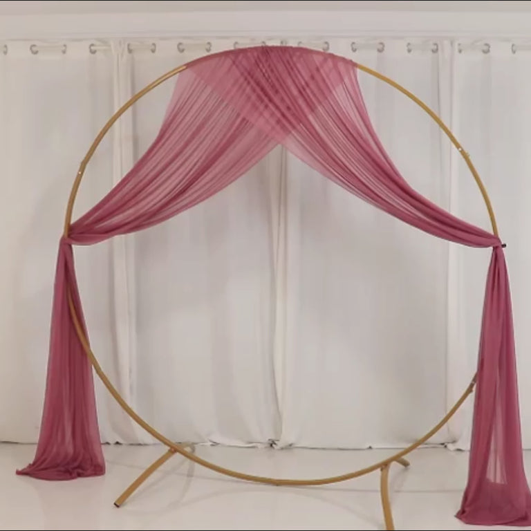 Mauve sheer wedding arch drape with golden frame against a white background.