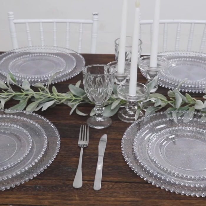 Clear silver glitter charger plates with beaded rim on a wooden table.