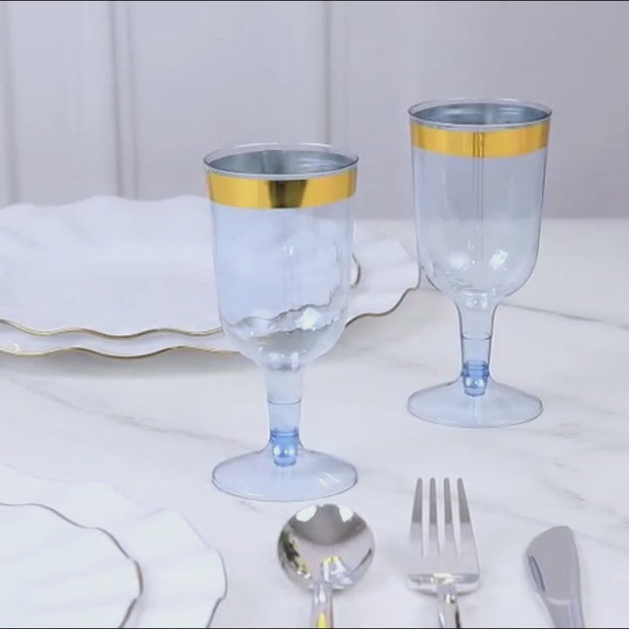 Dusty blue disposable wine glasses with gold rims on a table setting.