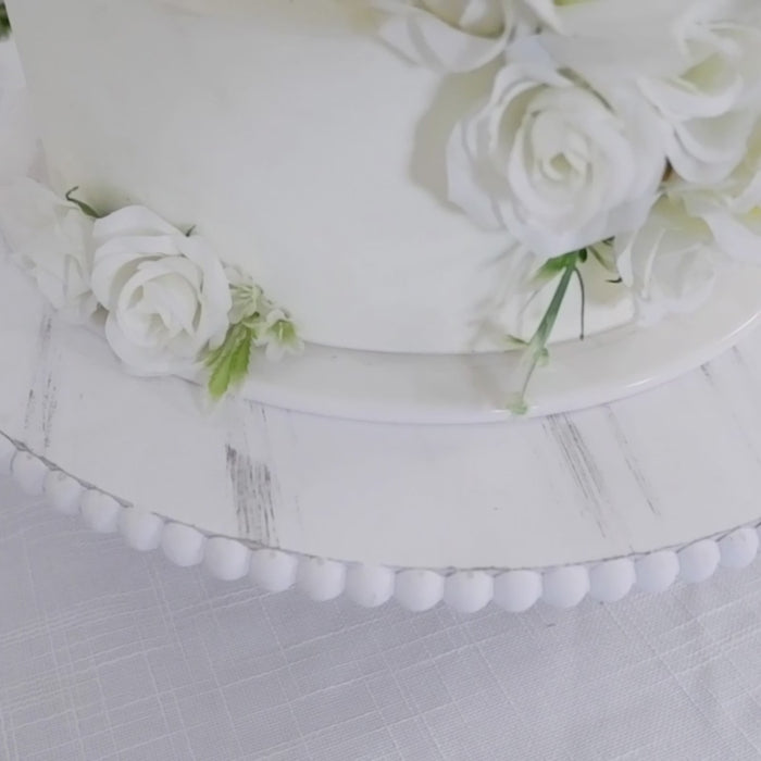 Antique white wooden pedestal cake stand with floral decoration.