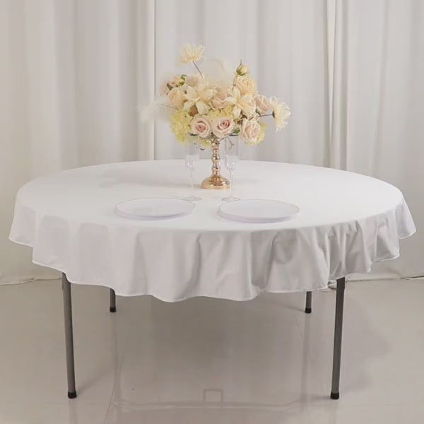 White round tablecloth on a table with floral centerpiece.