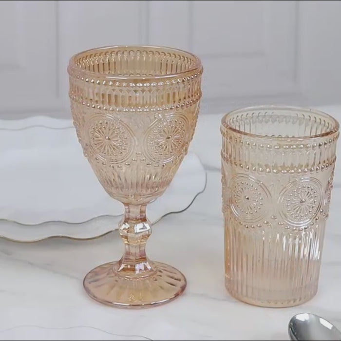 Amber gold textured glass tumblers with floral pattern on a marble surface.