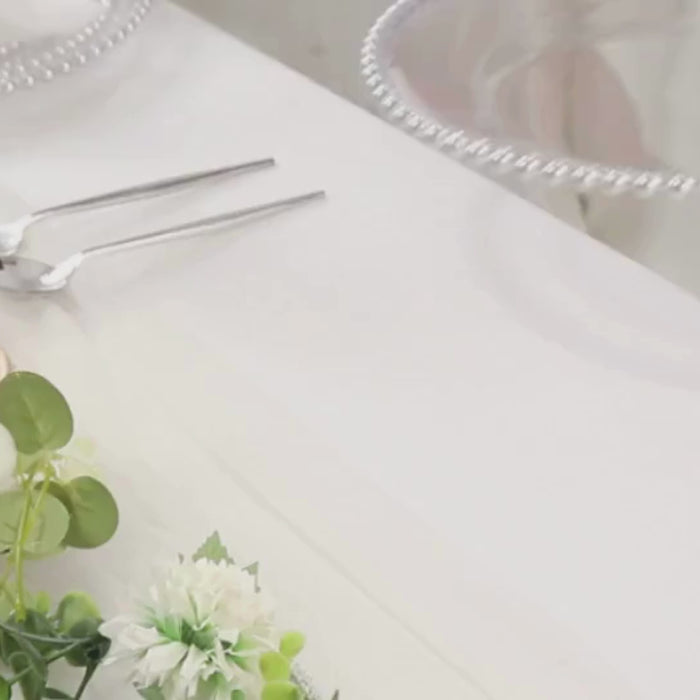 Clear plastic dessert plates with silver beaded rim on a table setting.