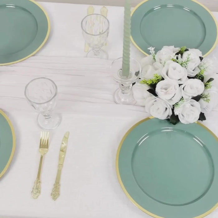 Dusty sage green charger plates with wide gold rim on a dining table setting.