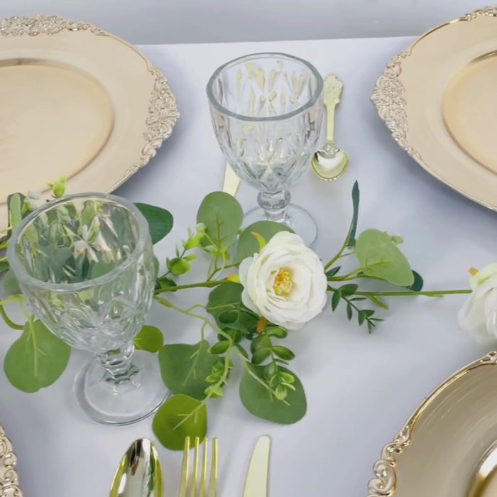 Gold embossed charger plates with antique baroque rim on a decorative table setting.