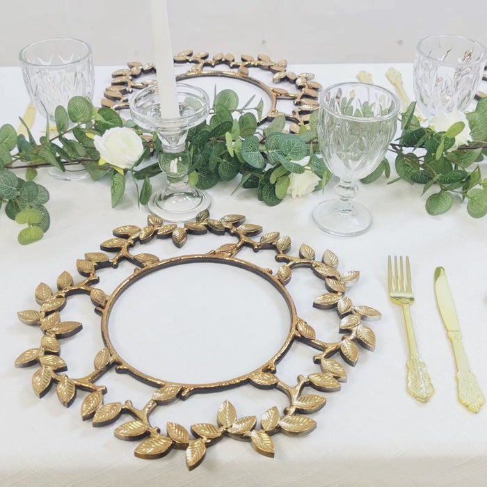 Gold charger plate with leaf wreath design on a decorated table setting.