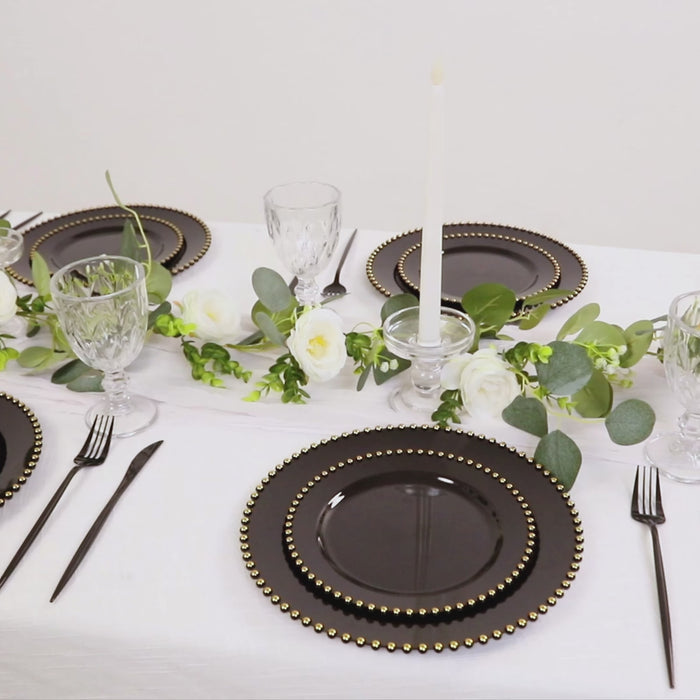 Black round dinner plates with a gold beaded rim on a table setting.