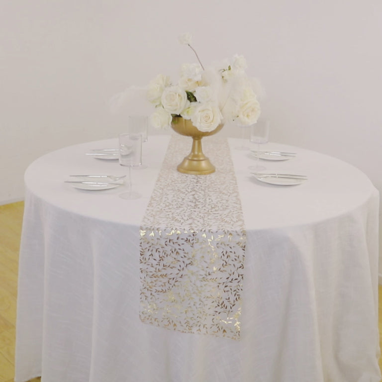 White organza table runner with gold foil leaf vines on a round table setting.