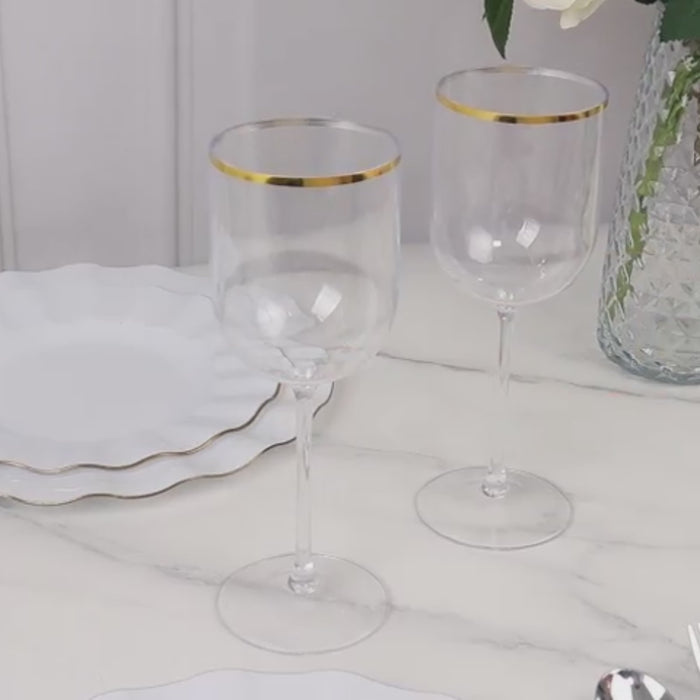 Clear plastic wine glasses with gold rim on a marble table.