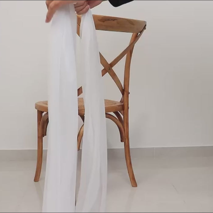 White sheer chair sash draping elegantly on a wooden chair.