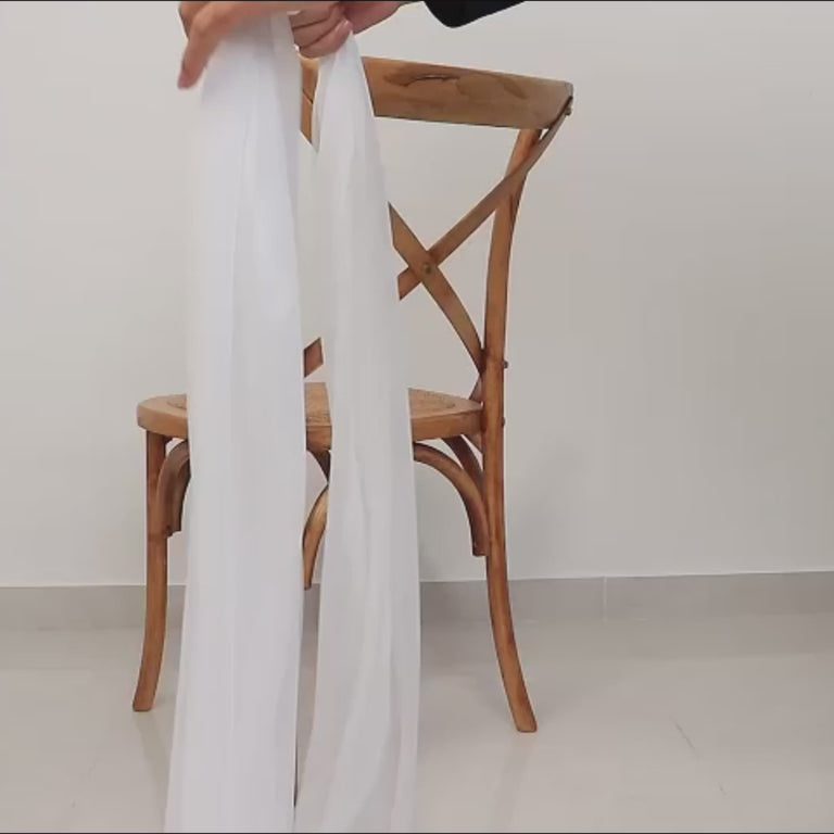 White sheer chair sash draping elegantly on a wooden chair.