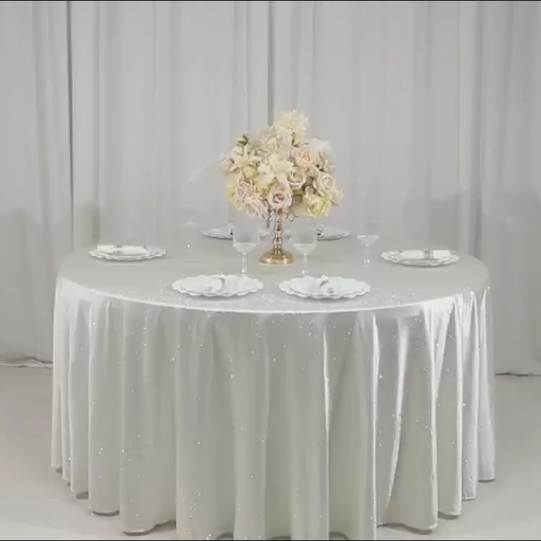 Pearl white round tablecloth with rhinestone accents on a dining table.