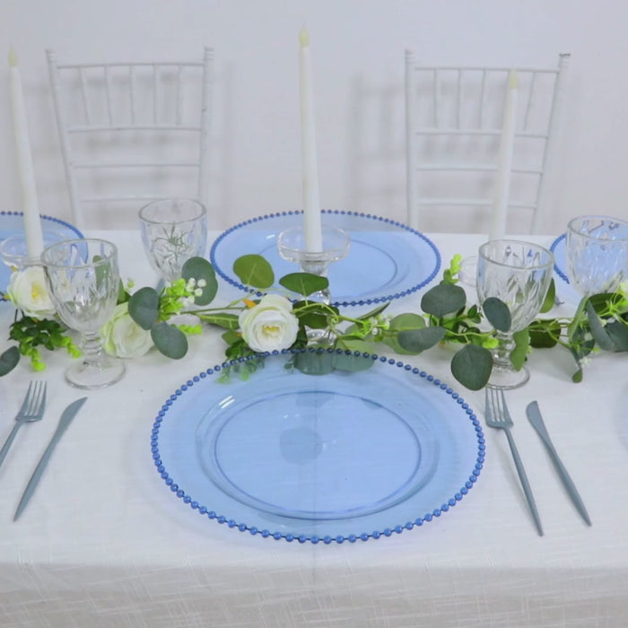 Dusty blue beaded rim charger plates on a decorated dinner table.