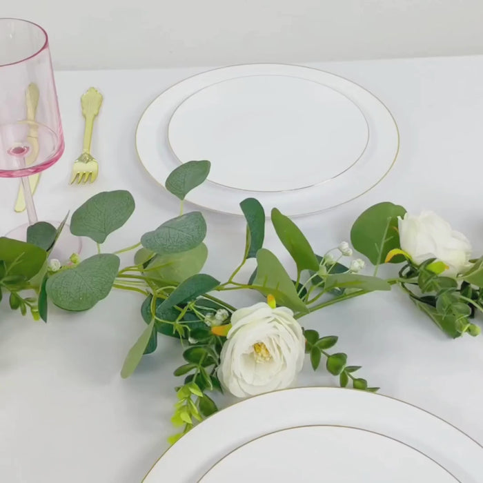 Transparent blush plastic wine glasses on a dining table with white plates and greenery.