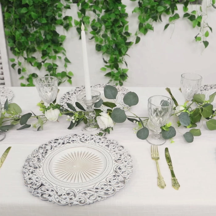 Antique white charger plate with vintage floral carved rim on an elegant table setting.