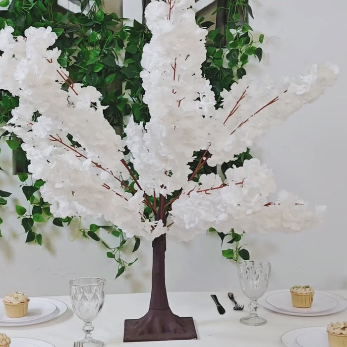 White artificial cherry blossom tree centerpiece on a dining table.