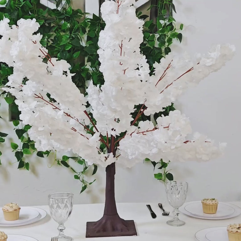 White artificial cherry blossom tree centerpiece on a dining table.