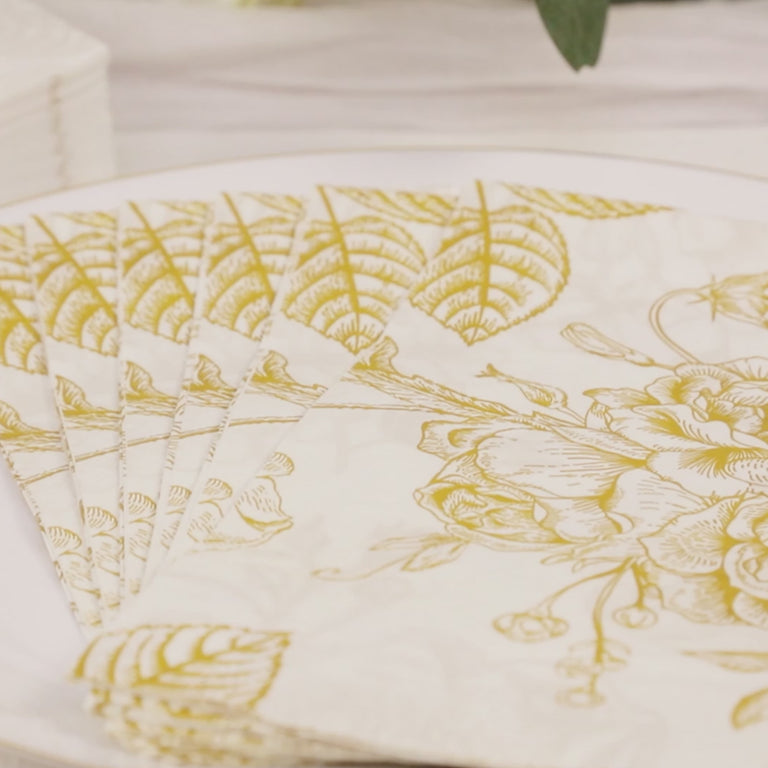 White paper cocktail napkins with gold floral pattern.