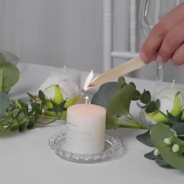 Clear glass candle holder plate with beaded rim and a lit candle.