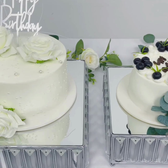 Silver crystal cake stands with mirror tops displaying decorated cakes.