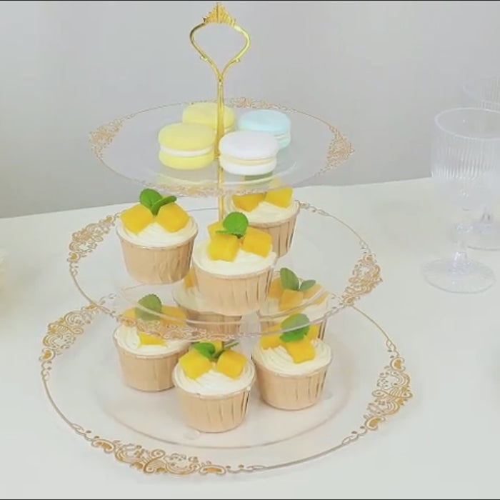 Clear plastic cupcake stand with silver embossed rim, displaying desserts.