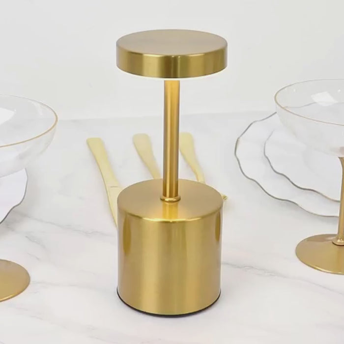 Gold cordless LED table lamp with touch control on a marble surface.