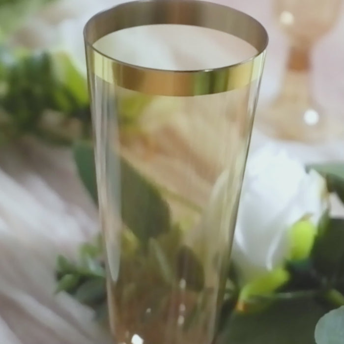 Amber gold champagne flute with gold rim on a decorative background.