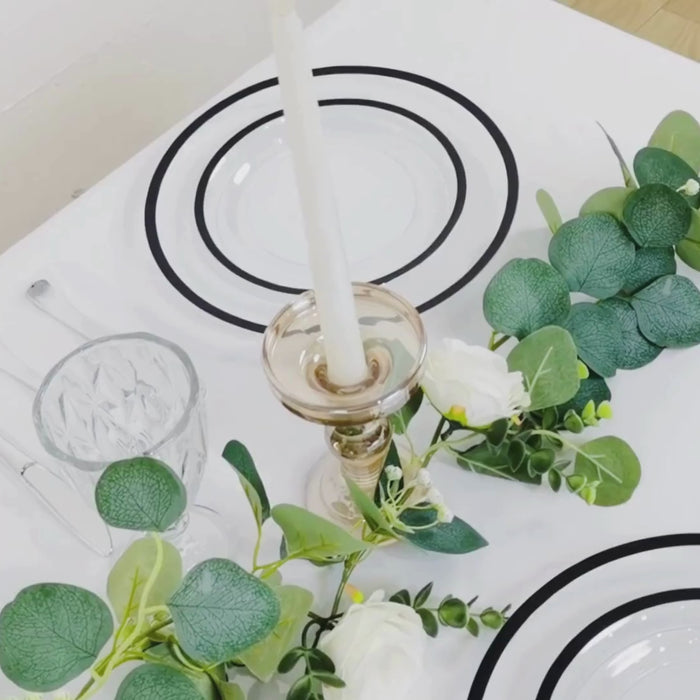 Clear plastic round dinner plates with black rim on a table setting.