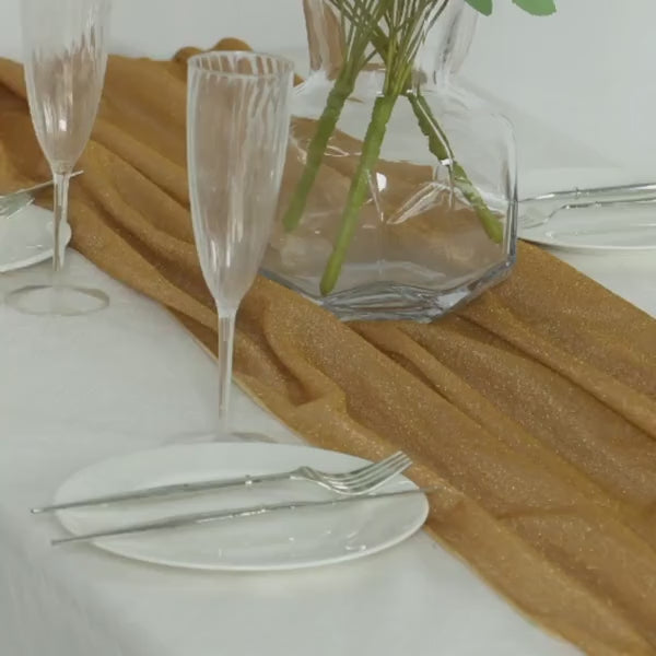 Gold glitter gauze table runner on a white table setting.