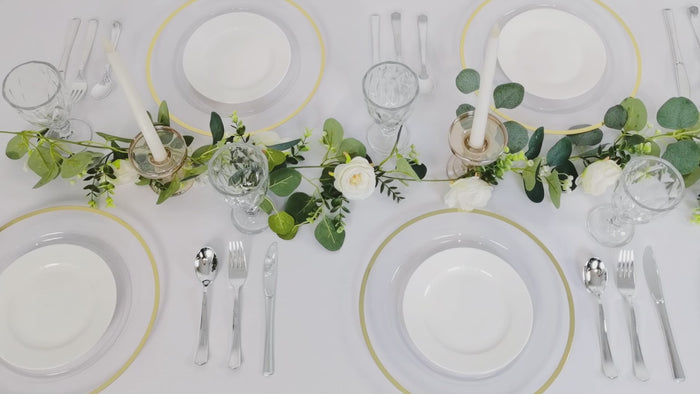 Clear charger plates with wide gold rim set on a table for a dinner party.