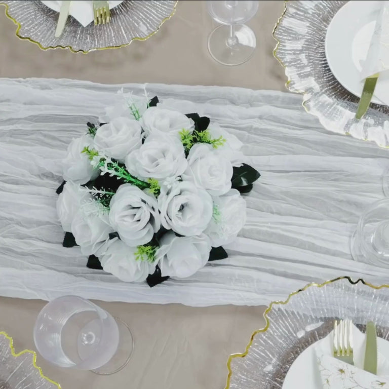 White gauze cheesecloth table runner with floral centerpiece on a banquet table.
