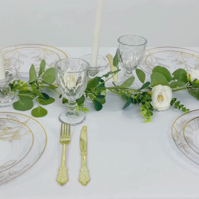 Clear plates with metallic gold floral design on a white table setting.
