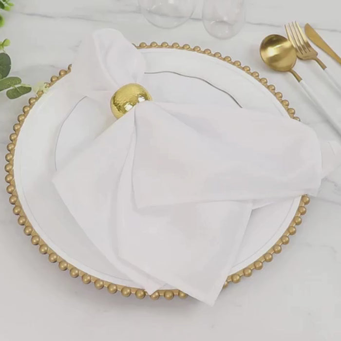 White charger plate with gold beaded rim, styled with a napkin and decorative elements.