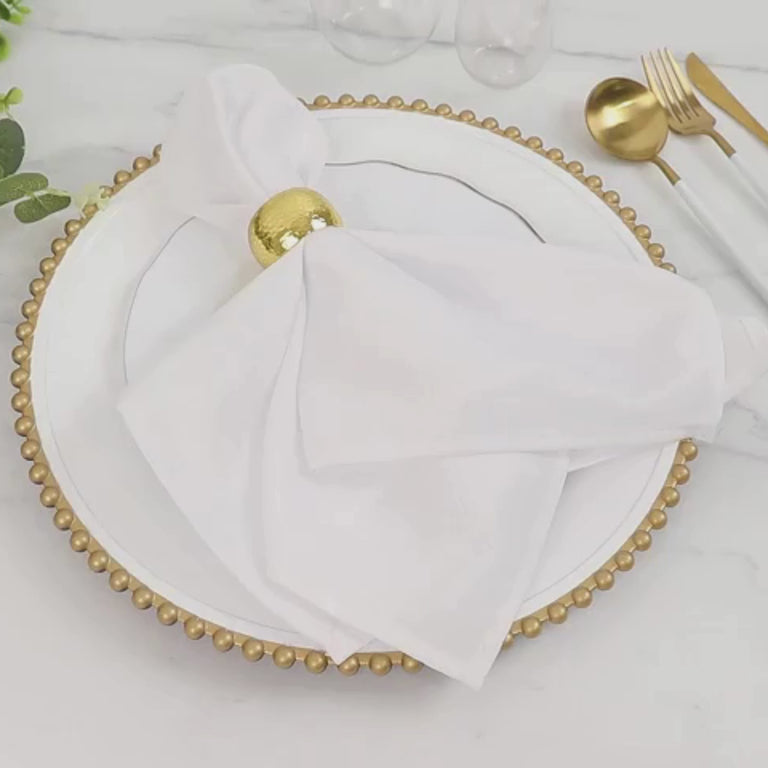 White charger plate with gold beaded rim, styled with a napkin and decorative elements.