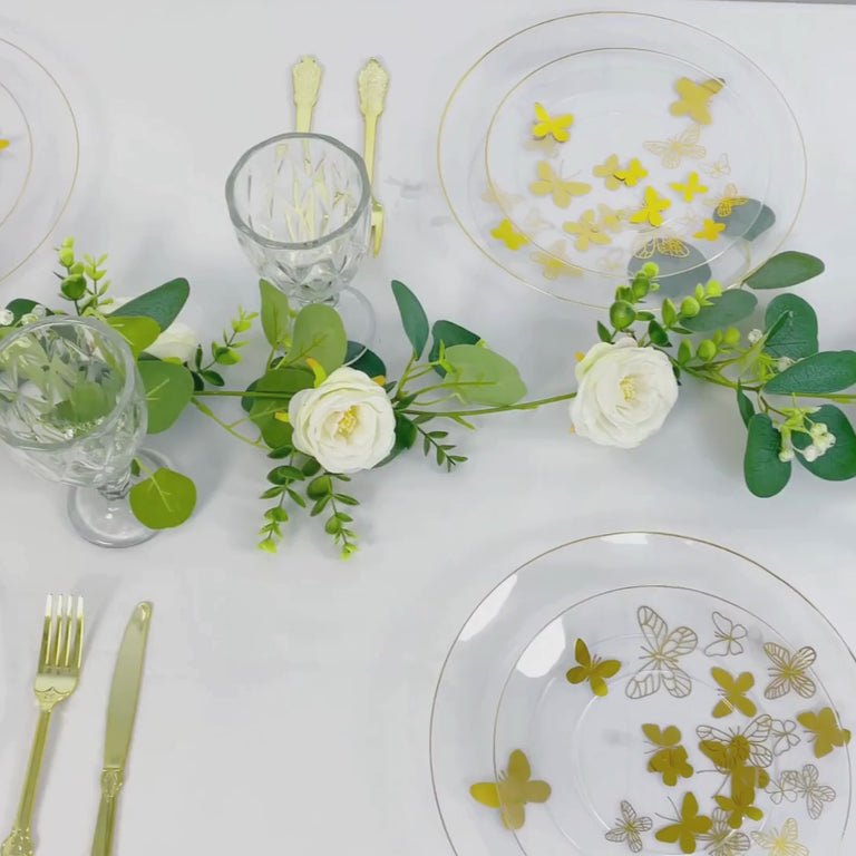 Clear plates with gold butterfly design and gold rim on a white table setting.