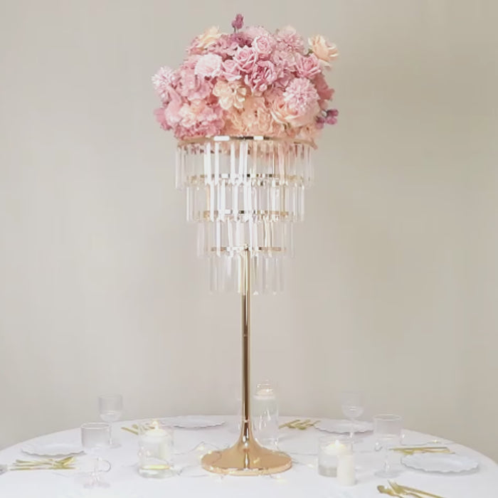 Gold metal flower stand chandelier with hanging crystals and pink floral arrangement.