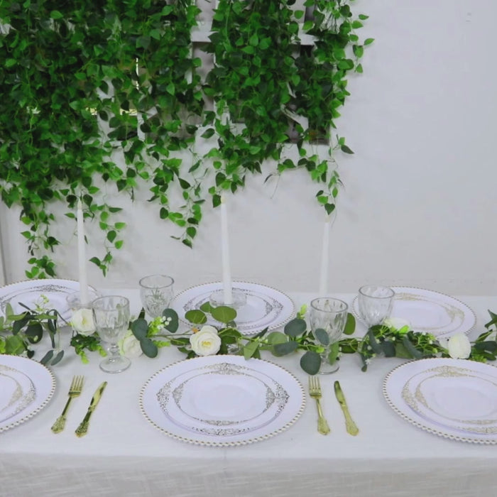 White charger plates with gold beaded rim on an elegantly set dinner table.