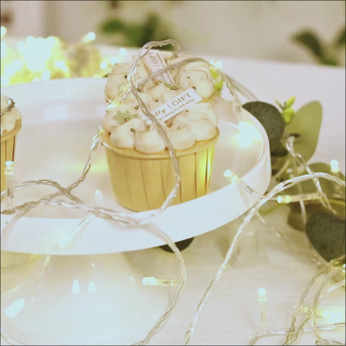 Warm white LED curtain string lights on a table with decorative cupcakes.