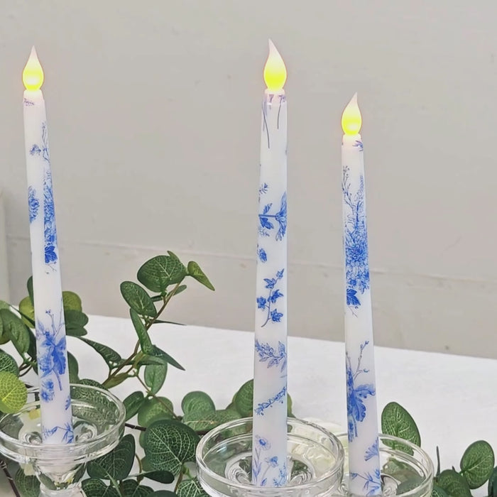 Blue flameless taper candles with flickering flames in glass holders.