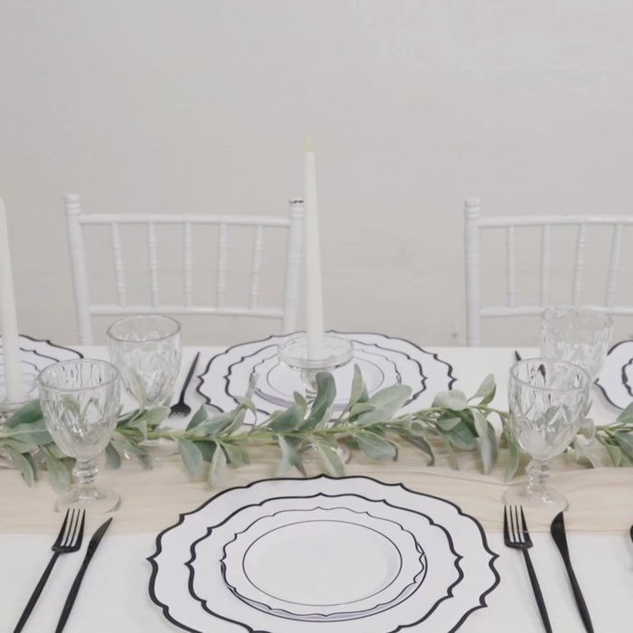 White disposable dessert plates with black scalloped rim on a table setting.