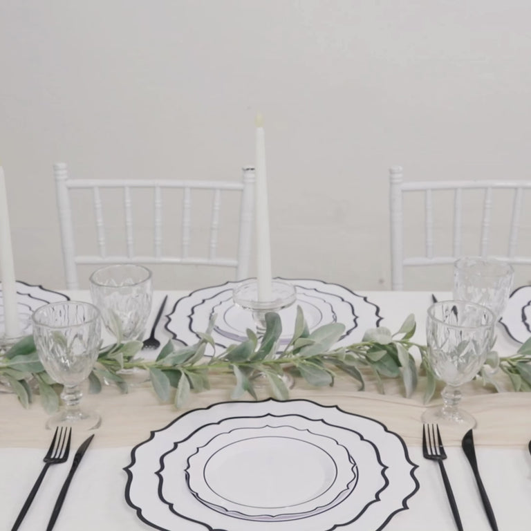 White disposable dessert plates with black scalloped rim on a table setting.