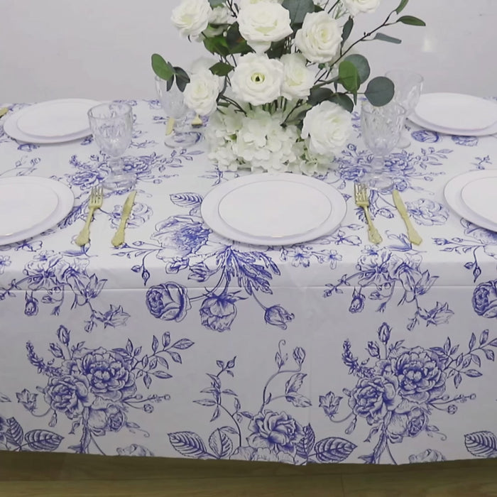White and blue French toile rectangular plastic tablecloth on a dining table.