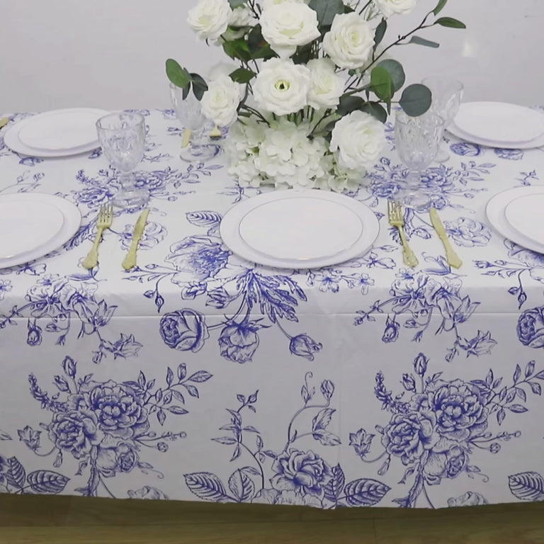 White and blue French toile rectangular plastic tablecloth on a dining table.