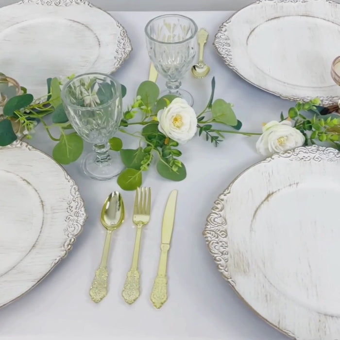 White washed charger plates with gold embossed rim on a decorative table setting.
